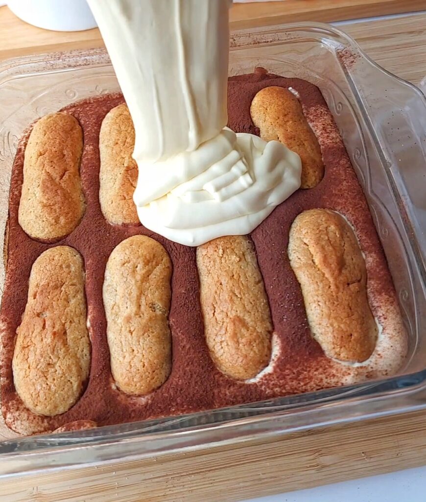 Assembling sugar free tiramisu. Square baking dish with ladyfingers and mascarpone cream