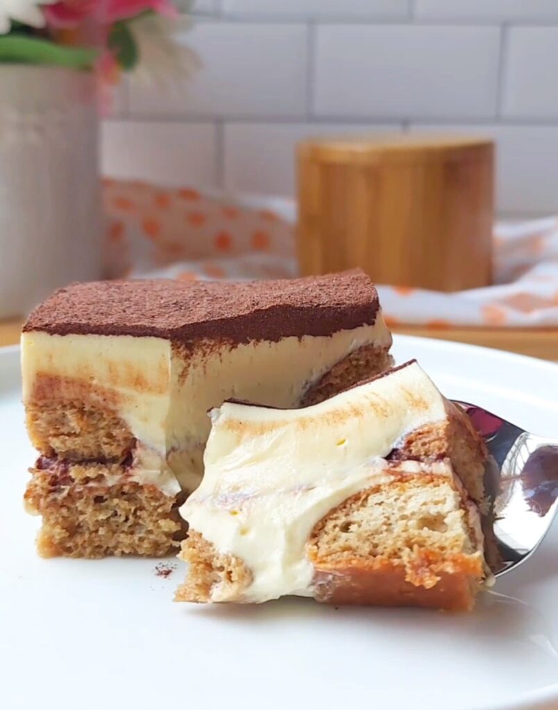 A spoon scooping up a bite of sugar free tiramisu on a plate