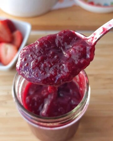 A spoonful of no sugar added chia jam hovering over the jam jar