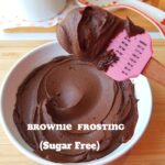 Brownie batter frosting in a white bowl. Scooped with a pink rubber spatula
