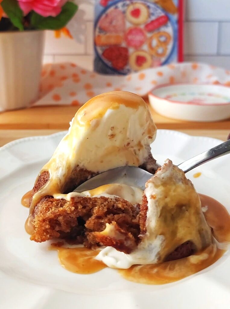 Warm sticky toffee pudding being eating with sugar free ice cream. Saucy on a white plate