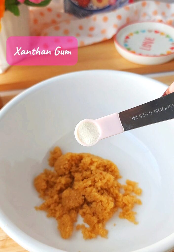 A quarter teaspoon of xanthan gum in a pink measuring spoon